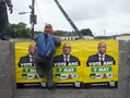 ANC election posters featuring images of South Africa's President Zuma are displayed on a wall as a school boy climbs over it in Embo