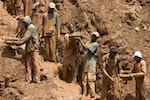 Gold miners form a human chain while digging an open pit in north-eastern Congo