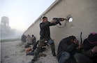 File photo of a Free Syrian Army fighter firing a rifle during an attack on a Syrian Army base in Damascus