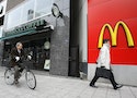 A cyclist and a pedestrian are seen outside branches of Starbucks and McDonald's in the Jimbocho district of Tokyo