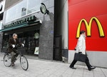A cyclist and a pedestrian are seen outside branches of Starbucks and McDonald's in the Jimbocho district of Tokyo