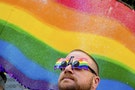 John Lucas stands in front of a rainbow flag at the San Francisco Gay Pride Festival in California