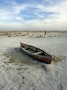 Kazakh man walks past a boat lying in sand that once formed the bed of the Aral Sea, near the ...