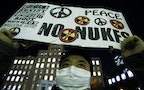 An anti-nuclear protester holds up a placard in front of a branch of Kansai Electric Power Co, the operator of the Ohi nuclear power plant which has been shut down, in Tokyo