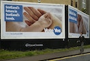 A man walks past a pro-independence poster by the seaside in Aberdeen