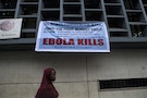 A woman passes a sign posted in an awareness campaign against the spread of Ebola in Freetown