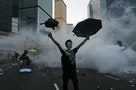 A protester raises his umbrellas in front of tear gas which was fired by riot police to disperse protesters blocking the main street to the financial Central district outside the government headquarte