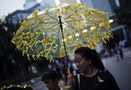 A woman holds a umbrella with yellow ribbons as she walks along a street blocked by protesters of the government headquarters in Hong Kong