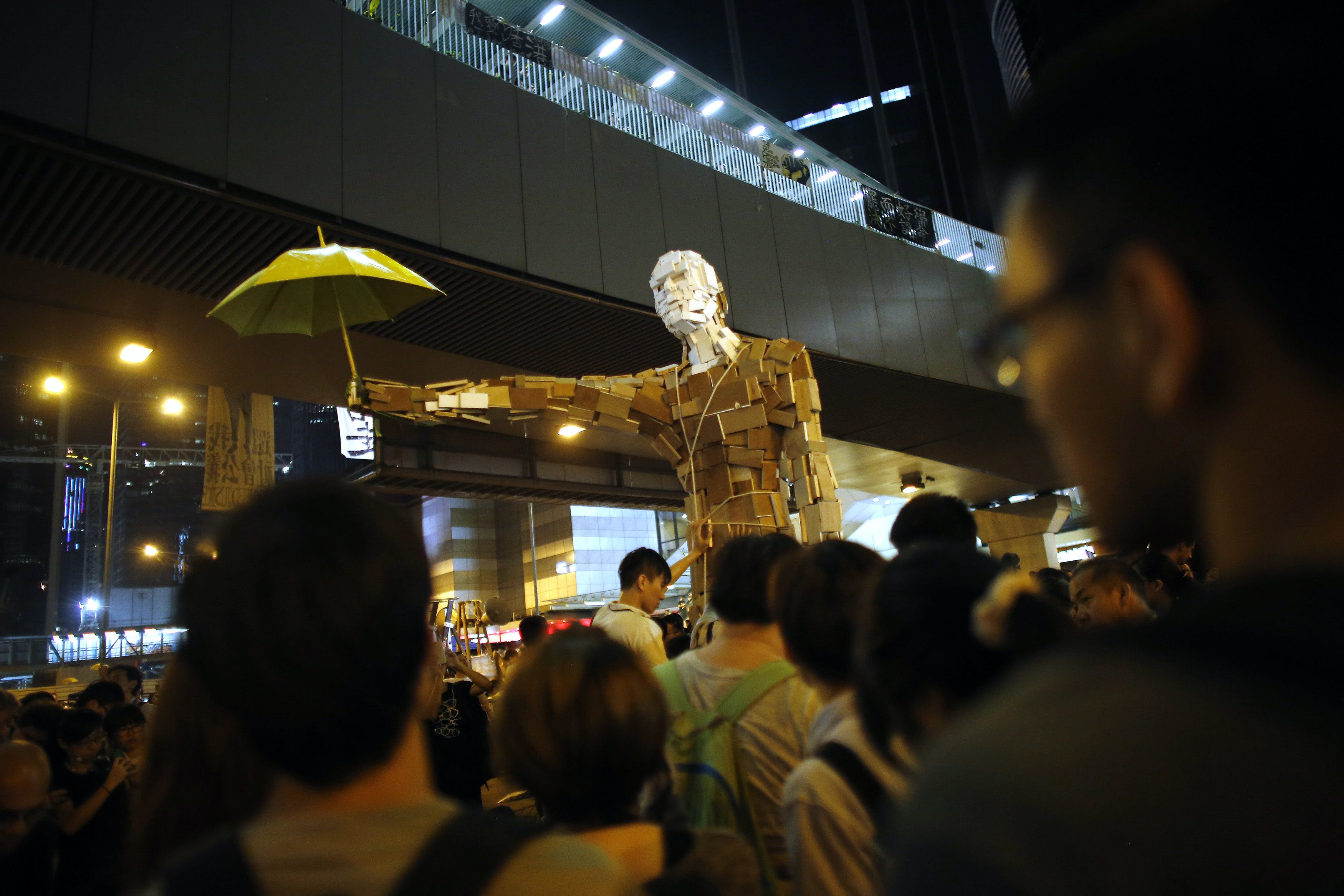 Protesters install a statue with a yellow umbrella as other demonstrators block the main street to the financial Central district in Hong Kong