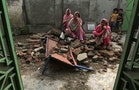 Villagers sit on the debris of their house after it was damaged during the recent exchange of fire between Pakistan and India at the Pakistani border town of Dhamala Hakimwala
