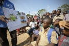 A man shows a picture chart regarding the Ebola virus to students during a United Nations Children's Fund (UNICEF) Ebola awareness drive in Toulepleu