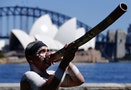 Aboriginal man plays a traditional musical instrument called a didgeridoo as he performs a "Welcome to Country" ceremony in front of the Sydney Opera House