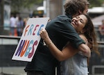 A visitor to the site of Sydney's cafe siege receives a hug from Youssy Mikhail, one of several people offering 'free hugs' to members of the public during a public outpouring of emotion from the tragedy