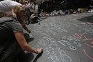 Members of the public write messages of condolence in chalk on the pavement near the site of the Sydney cafe siege in Martin Place