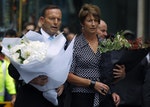 Australian Prime Minister Tony Abbott and his wife Margie prepare to place floral tributes  near the cafe in central Sydney where hostages were held for over 16-hours