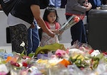 A girl prepares to lay a bouquet among thousands of others at an impromptu memorial site near the Sydney cafe siege in Martin Place