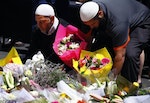 Members of the Australian Muslim community place floral tributes near the Lindt cafe in Sydney