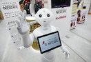SoftBank Corp's human-like robot named Pepper" gestures as it introduces Nestle's coffee machines at an electric shop in Tokyo