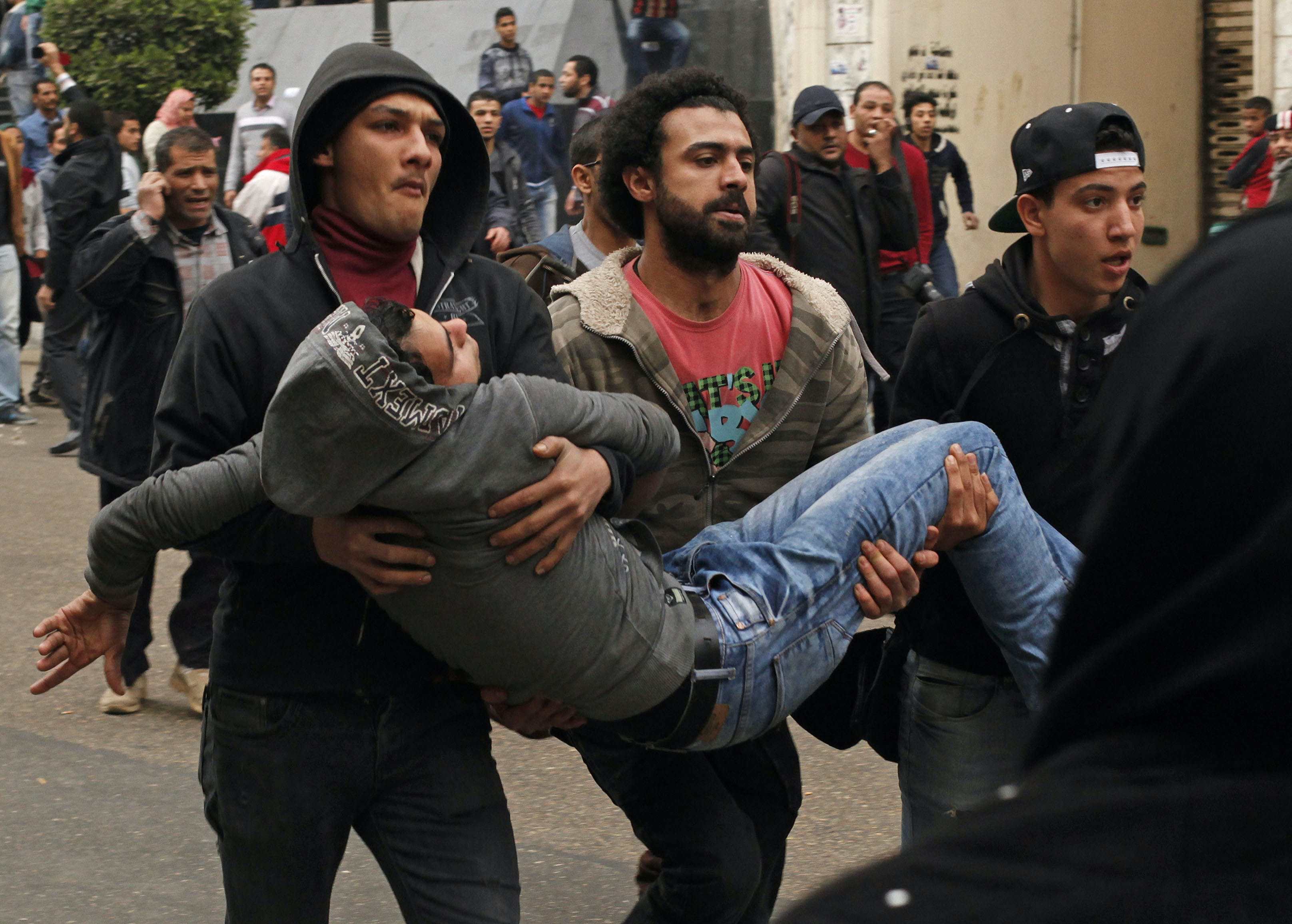 Anti-government protesters help an injured protester when pro-government protesters threw stones during a protest in Cairo