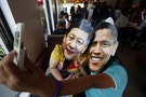 Members of activist Party List group "Akbayan" wearing picture cut-out masks of U.S. President Barack Obama and China's President Xi Jinping make a "selfie" with a mobile phone in a coffee shop in Que