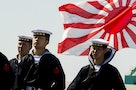 Soldiers of Japan's Maritime Self Defense Force stand in front of the country's naval ensign during the handing-over ceremony of the Izumo warship at the Japan United Marine shipyard in Yokohama