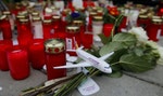 Flowers and lit candles are placed on the ground in Cologne Bonn airport
