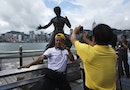 A tourist poses in front of a bronze statue of the late kung fu legend Bruce Lee on the waterfront of Hong Kong