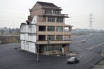 A car stops beside a house in the middle of a newly built road in Wenling
