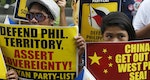 Protesters display placards as they march to the Chinese consulate office in Makati