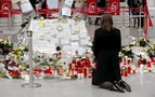 Woman kneels in front of candles and flowers as she prays for the victims of Germanwings Flight 4U9525 at Duesseldorf airport
