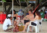 A group of tourists holds their beer while relaxing at Kuta beach on Bali resort island