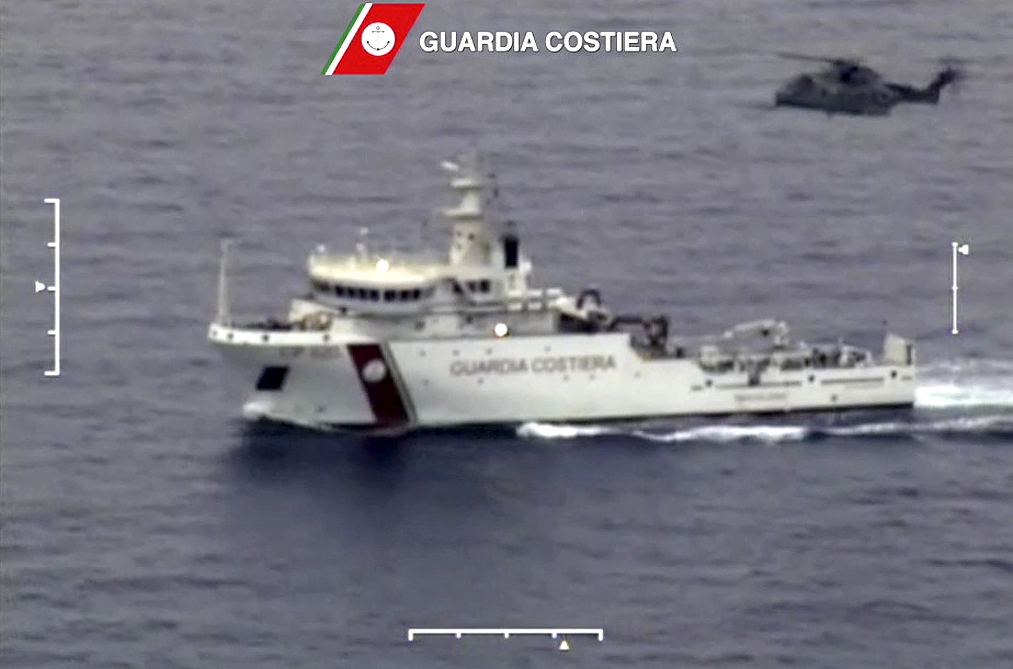 An Italian coast guard vessel is seen with an helicopter during the search and rescue operation underway after a boat carrying migrants capsized overnight, in this still image taken from video