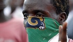 A protestor covers his face with a scarf during clashes with riot police as he takes part in a rally against the ruling CNDD-FDD party's decision to allow President Pierre Nkurunziza to run for a thir