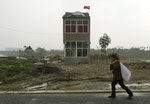 A woman walks past a nail house, the last house in this area, on the outskirts of Nanjing