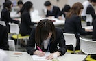 Japanese job-hunting students dressed in suits attend a business manners seminar at a placement centre in Tokyo