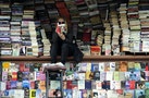 A woman reads a book at her open air book store in Skopje