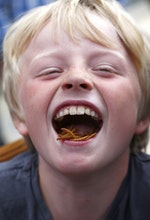 Stan Knight, age nine, poses for a photograph as he eats barbecued mealworms at a pop-up restaurant in central London