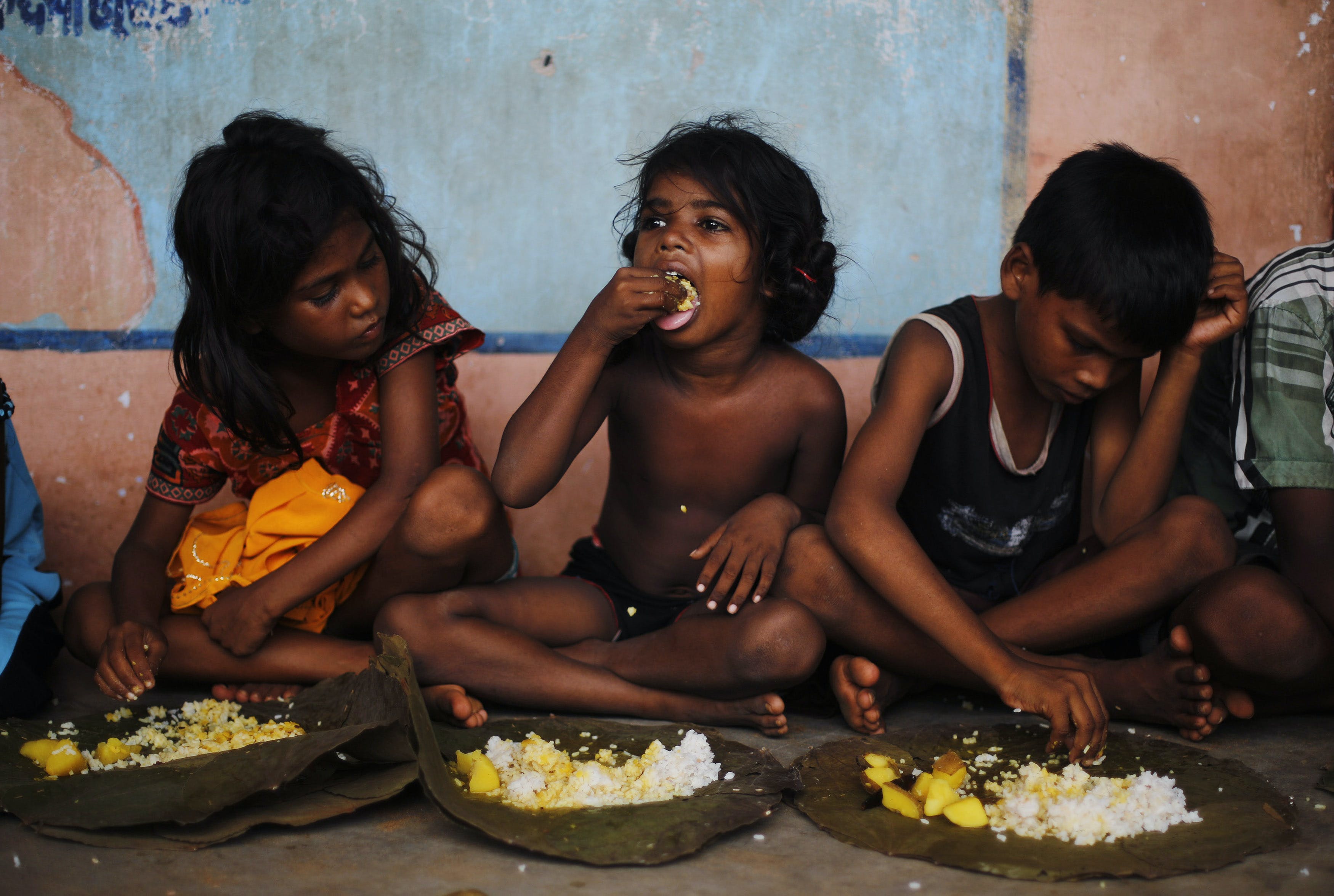 Children eat their lunch in a free meal centre at the cyclone-hit Gopalpur village