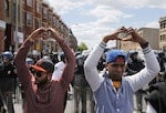 Members of the community make heart gestures with their hands in front of a line of police officers in riot gear, near a recently looted and burned CVS store in Baltimore