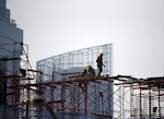 Workers walk on scaffolding at a construction site for new apartments in Jakarta May 22, 2015.  Indonesia's central bank will ease mortgage downpayment requirements for first-home buyers as it tries to revive economic growth without cutting interest rates. Bank Indonesia (BI) kept interest rates unchanged this week, shrugging off political pressure for a cut aimed at turning around the worst economic slowdown since 2009.  REUTERS/Darren Whiteside  - RTX1E2TG