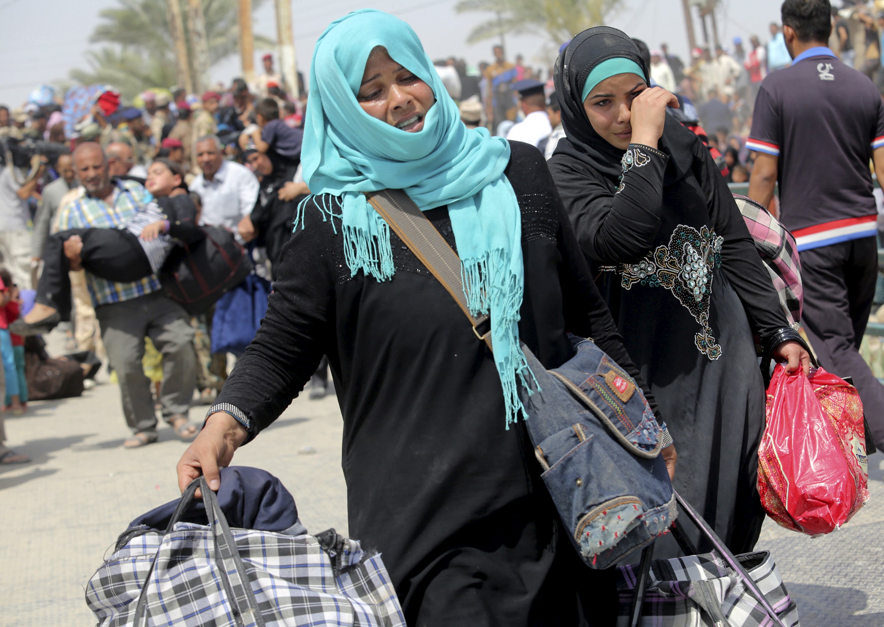 Displaced Sunni women fleeing the violence in Ramadi, carry bags as they walk on the outskirts of Baghdad