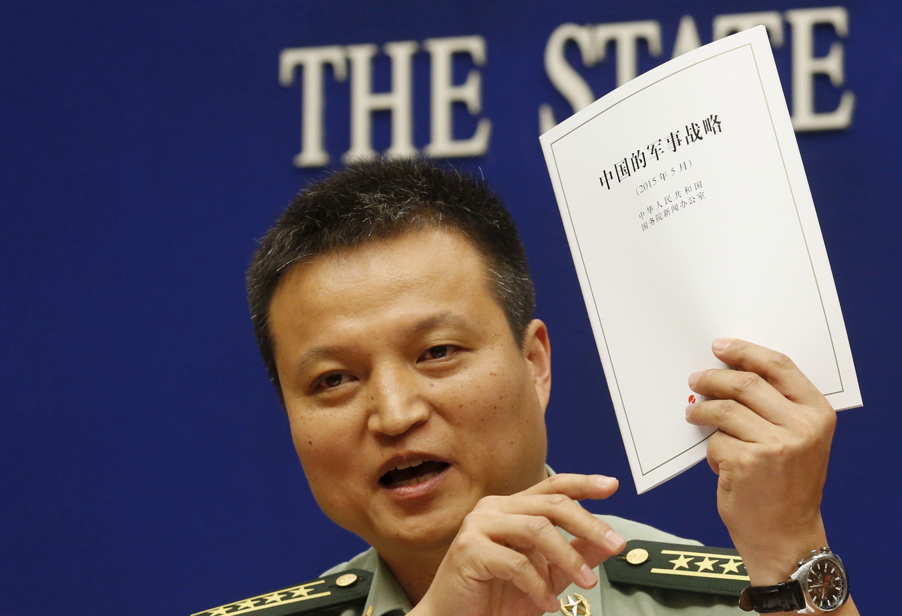 Spokesperson of Chinese Ministry of National Defense Senior Colonel Yang holds a copy of the annual white paper on China's military strategy during a news conference in Beijing