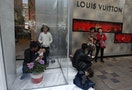 A mainland Chinese visitor feeds his baby outside a Louis Vuitton store in Hong Kong