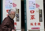 A woman wearing a medical mask walks past vending machines that sell masks outside National Taiwan University Hospital in Taipei