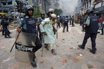 Police officers help a man cross a street during a clash with activists of Hefajat-e Islam in Dhaka