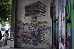 【坐在民主上想者未來與生存】雅典街頭一幅希臘債務危機的壁畫。過去，雅典街頭塗鴉充斥足球、政治或年輕人著迷的議題。現在，大部分的嚴肅議題都是受到該國的財政和社會危機所啟發。Photo Credit: AP/達志影像