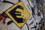 【快跳水吧！】 一位化名Wild Drawing的街頭藝術家者，在牆上畫出一幅名為「遠離」的塗鴉作品。在這個假路標中，一輛帶有希臘藍白色國旗的汽車從搖搖欲墜的歐元符號中跳水。Photo Credit: AP/達志影像