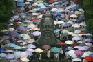Students holding umbrellas walk past a statue of Confucius after the second day of the National College Entrance Exams in Wuhan