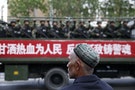 新疆＿維吾爾＿A Uighur man looks on as a truck carrying paramilitary policemen travel along a street during an anti-terrorism oath-taking rally in Urumqi