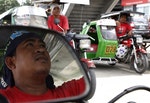 Tricycle taxi driver Arnold Bolata is reflected in the side mirror of his vehicle in Quezon city, Manila